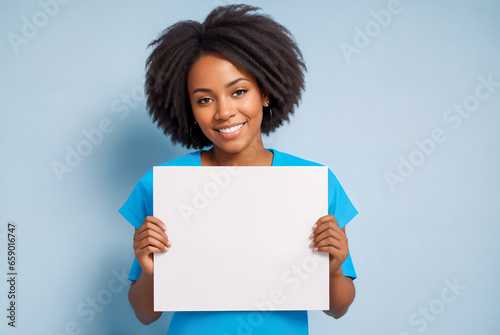 Black woman holding white sign paper in her hands and smiling at the camera with blue background.Minimalism.Creative designer fashion glamour art.
