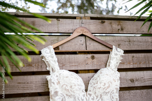 White lace wedding gown hanging on wooden plank fence in Florida