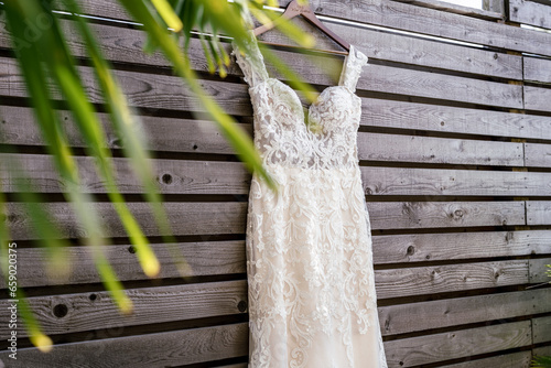 White lace wedding gown hanging on wooden plank fence in Florida