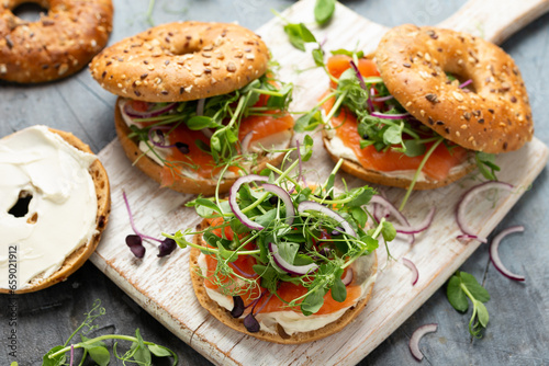 Smoked salmon and soft cheese seeded bagel with pea and purple reddish shoot salad and red onion. Protein packed breakfast concept