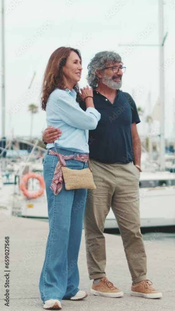 An elderly couple are walking along the promenade and having fun chatting on yacht background An elderly couple are walking along the promenade and having fun chatting on yacht background