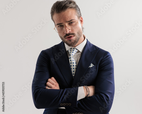 confident young businessman with glasses crossing arms and looking forward