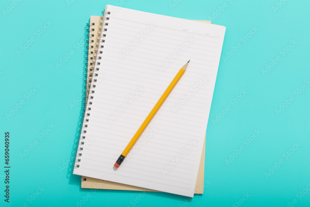 Top down view of empty light colored notebooks with pencil on colored backgrounds Top down view of empty light colored notebooks with pencil on colored backgrounds