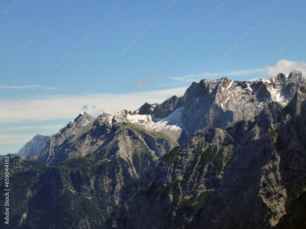 Rocky slopes of high mountains with a blue horizon covered with snow and greenery. Beautiful natural landscape