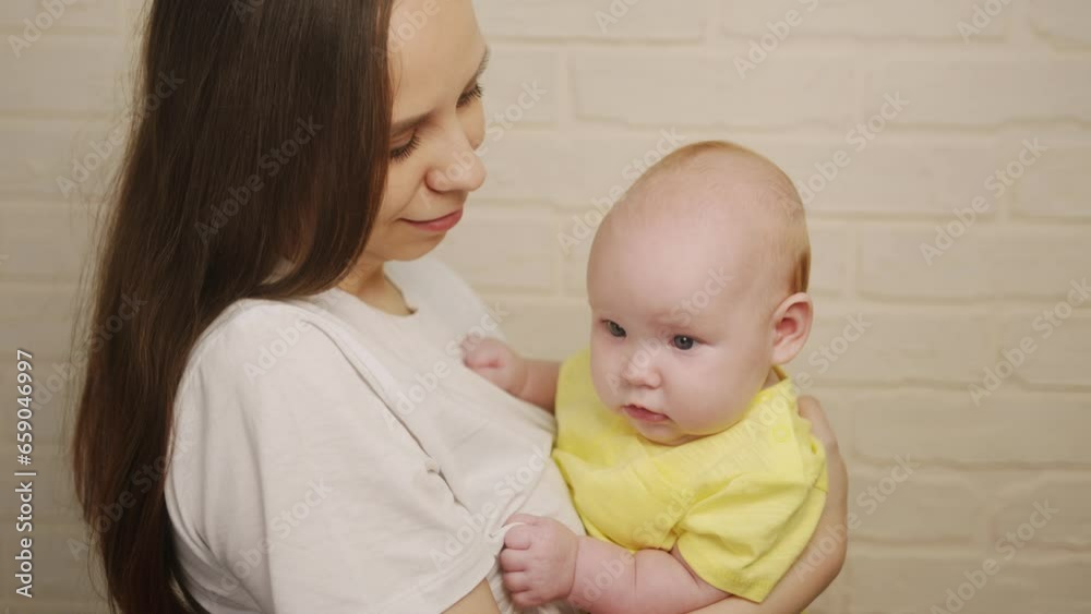 Young mother with her newborn baby in her arms on white brick wall background Young mother with her newborn baby in her arms on white brick wall background