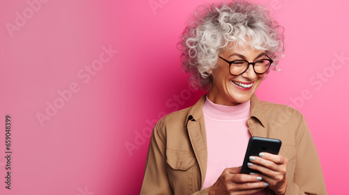 Elderly women smiling with her phone against a color background. 