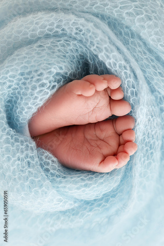 Close-up of tiny, cute, bare toes, heels and feet of a newborn girl, boy. Baby foot on blue soft coverlet, blanket. Detail of a newborn baby legs. Macro horizontal professional studio photo. 