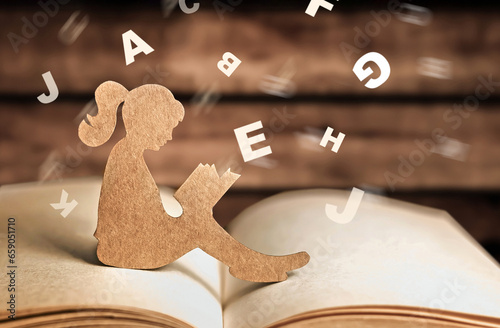 girl with dyslexia holds a book. Flying tangled letters in the air. The child learns to speak and read correctly