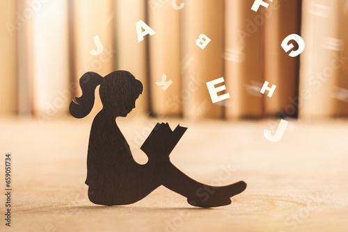girl with dyslexia holds a book. Flying tangled letters in the air. The child learns to speak and read correctly