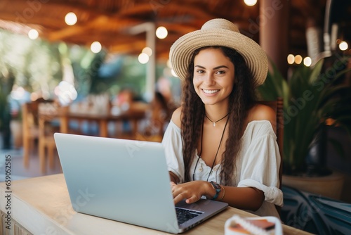 a young digital nomad woman with a hat working with her laptop in a bar