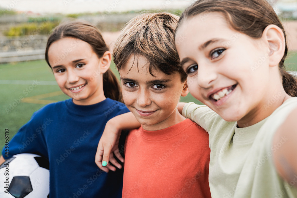 Kid friends after soccer play game having fun taking selfie outside - Latin children celebrating and hugging together - Childhood friendship and sport life style concept Kid friends after soccer play game having fun taking selfie outside - Latin children celebrating and hugging together - Childhood friendship and sport life style concept