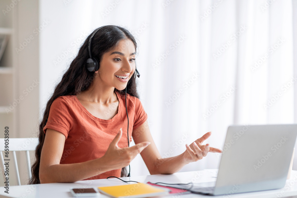Cheerful remote worker pretty indian woman using laptop and headset Cheerful remote worker pretty indian woman using laptop and headset