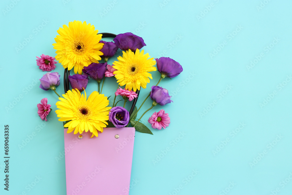 Top view image of pink, purple and yellow flowers composition over pastel blue background .Flat lay