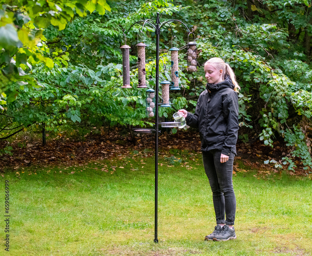 Φωτογραφία A woman or girl filling up water of a bird feeder
