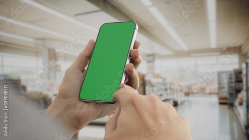 CU 30s Caucasian male holding a phone in grocery store  green screen