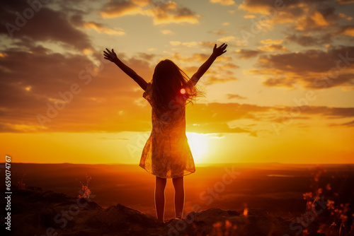 Preteen girl silhouette with raised hand over sunset sky embracing nature 