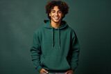 Young Hindu student in green hoodie and jeans stands happily 