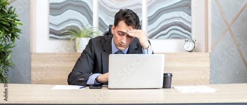 Tired frustrated and overworked business man sitting in the office and thinking about problems in business	