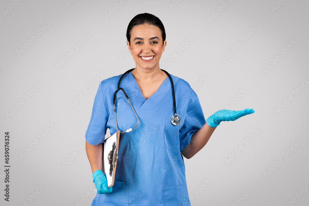 Doctor in blue uniform holds clipboard, presenting something on her palm Doctor in blue uniform holds clipboard, presenting something on her palm