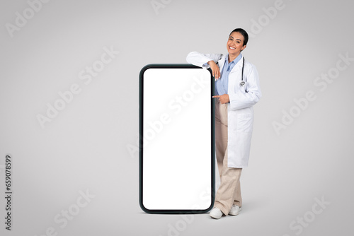 Quadro su tela Latin woman doctor by huge cellphone with blank screen., mockup