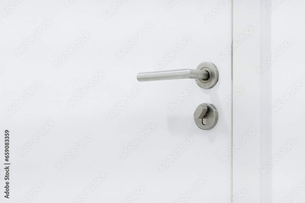 Metal door handle with lock on white wooden door. Close up of door handle on interio doors. Metal door handle with lock on white wooden door. Close up of door handle on interio doors.