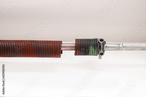 Broken garage door spring or torsion spring from overhead sectional door inside. Sheared-off spring has reached lifespan cycles or material failure. Selective focus.