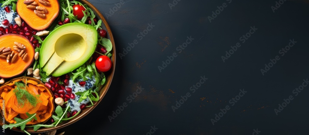 Autumn themed vegan salad with caramelized pumpkin red cabbage avocado arugula pomegranate and walnuts Comfort food Blue background Top view banner