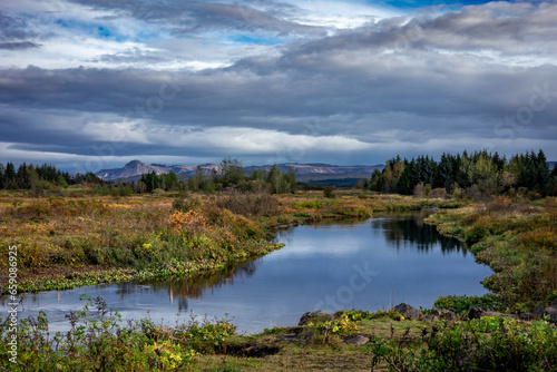 Autumnal landscape with Ellidaa river, forest and mountains in Reykjavik, Iceland. 