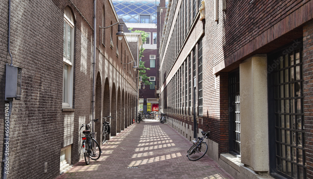 street in the old town of amsterdam, bicycles in alley - obrazy, fototapety, plakaty 