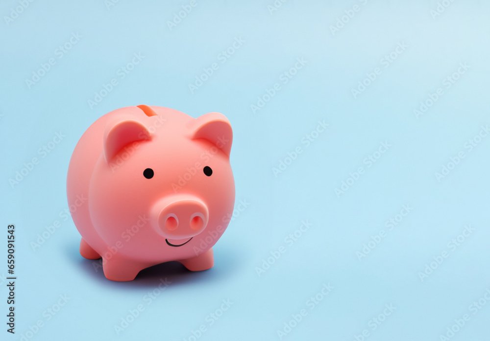 Pink piggy bank for money saving isolated on pastel blue background with copy space.