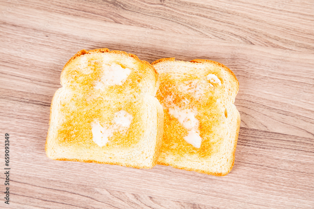 Two pieces buttered toast on a wooden cutting board Two pieces buttered toast on a wooden cutting board