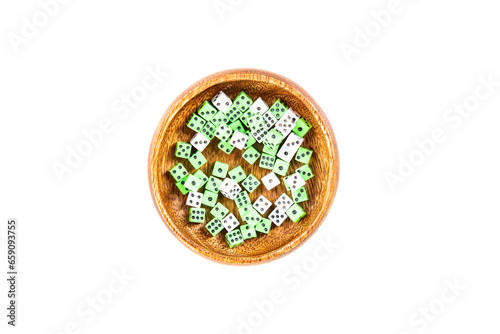Handful of tiny white and neon green dice in a wooden cup isolated over white