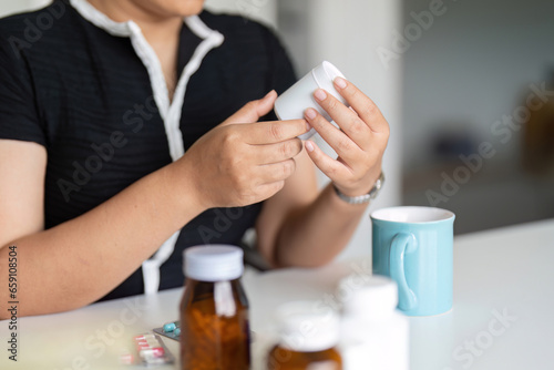 Woman hold bottle of drug tablet painkiller or vitamin supplement reading label ready to organizing medicine at home. medication healthcare concept