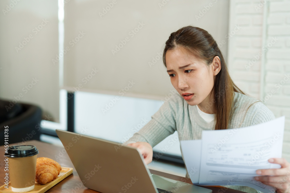 Beautiful Asian business woman in gray sweater sitting laptop, smiling happily sales, had his phone documents on display. Next to it croissant brown disposable coffee cup. In small business cafe Beautiful Asian business woman in gray sweater sitting laptop, smiling happily sales, had his phone documents on display. Next to it croissant brown disposable coffee cup. In small business cafe