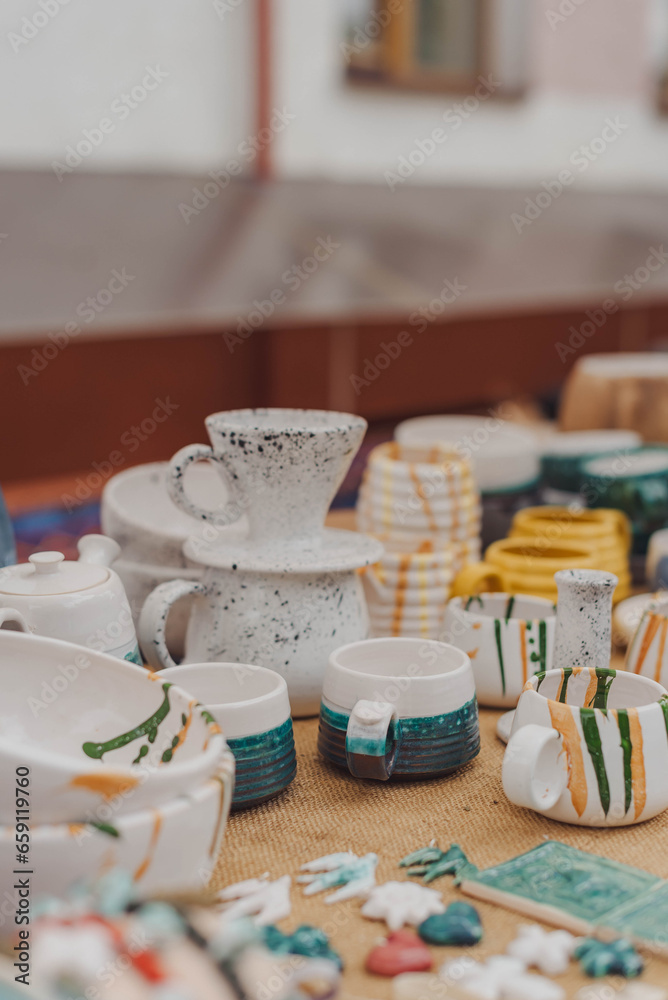 Naklejka premium handmade ceramics, empty craft ceramic plates, mug, cup and bowls at a street fair or flea market or street Sunday market. Selective focus.