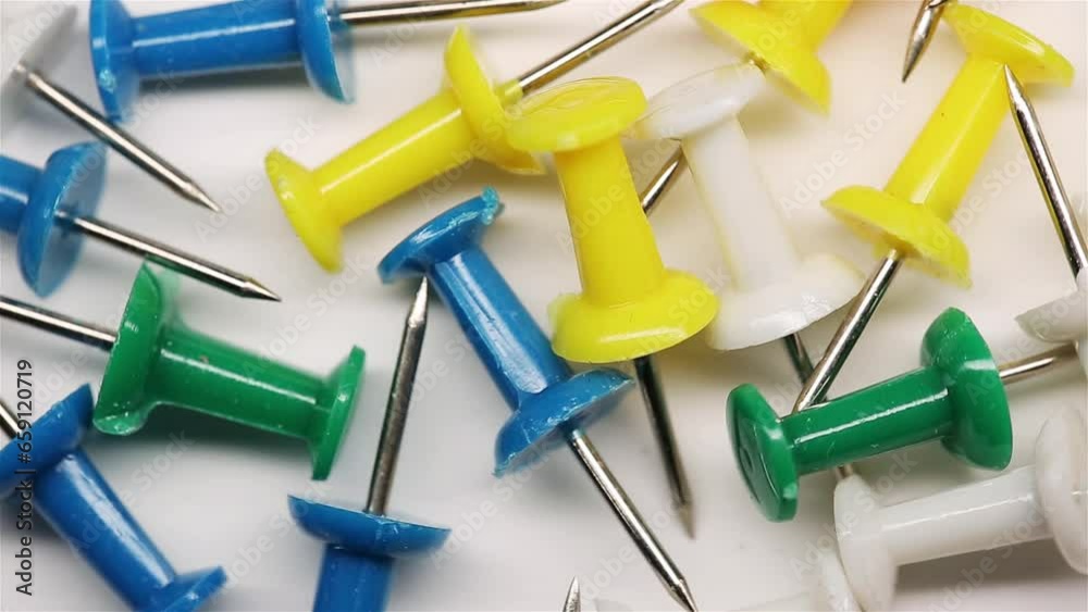 Colorful push pins rotating on the desk. Drawing pins for marking on the map of the Earth or city. Plastic pins. Macro Colorful push pins rotating on the desk. Drawing pins for marking on the map of the Earth or city. Plastic pins. Macro