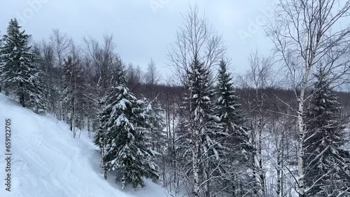 A chairlift at a ski resort on a cloudy winter day in the Ural Mountains. A lift on the background of factory pipes. Climbing the mountain. Gubakha, Perm Krai, 4K photo