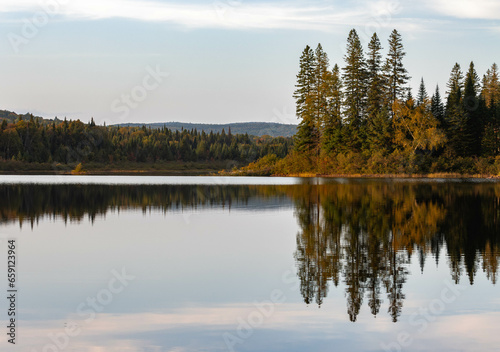 Mirror-like reflections on a lake of the autumn scenery of a Canadian forest with vibrant colors