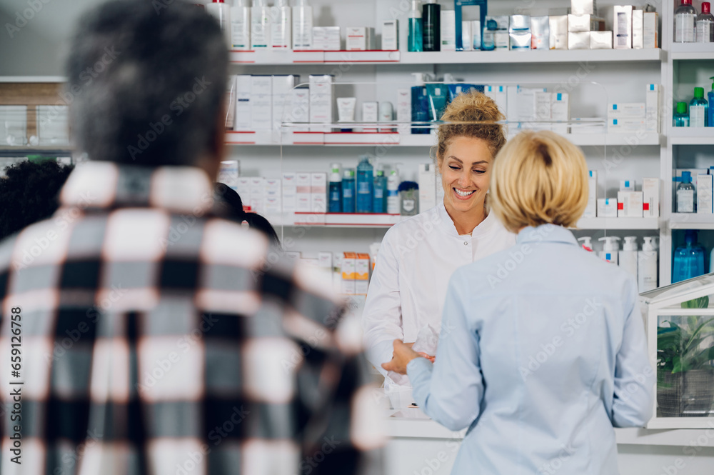 Portrait of a woman pharmacist selling drug to a senior customers in a pharmacy
