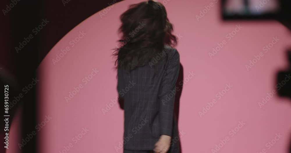 Backstage professional fashion photo shoot. Professional Asian model girl posing on pink-powder color background in the studio in white light of cyclorama. Modern youth people. No flash lights