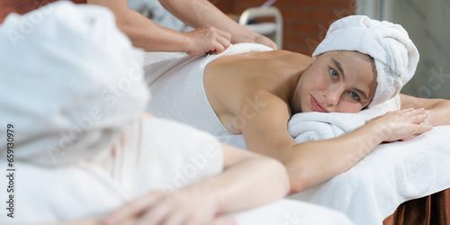 A portrait of two attractive young women with beautiful skin in white towel having a back massage by professional masseur at traditional spa salon. Beauty and healthy. Tranquility.