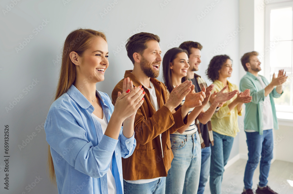 Group of happy joyful young people applaudding standing in a row. Friendly smiling successful coworkers and company employees clapping a colleague on a meeting or business conference. Group of happy joyful young people applaudding standing in a row. Friendly smiling successful coworkers and company employees clapping a colleague on a meeting or business conference.