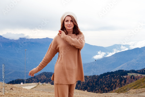 beautiful smiling caucasian woman in a beige ribbed fabric suit and beret in the mountains in autumn