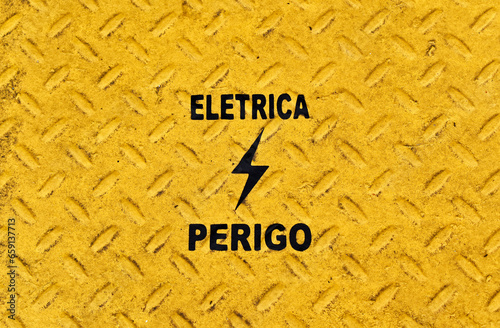 Yellow metallic surface with portuguese words that mean ELETRICITY and DANGER (Eletrica Perigo) photo