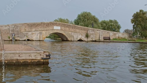 Potter Heigham, Norfolk, UK – October 07 2023. The medieval stone bridge, built c. 1385, over the River Thurne in Potter Heigham in the heart of the Norfolk Broads photo