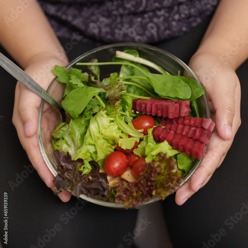 Overweight woman enjoy eating a bowl of vegetable salad at her home