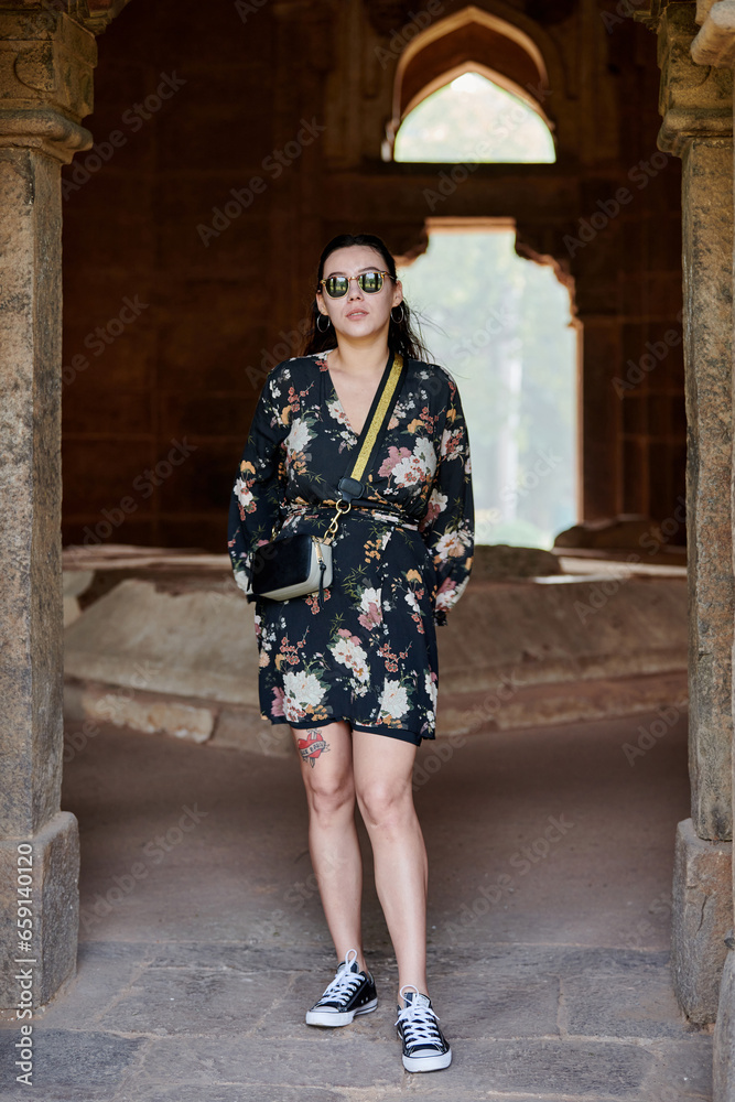 Attractive east asian woman in black sunglasses and dress stands in ancient indian tomb Attractive east asian woman in black sunglasses and dress stands in ancient indian tomb