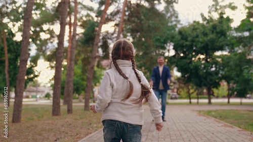 Joyful little daughter runs to embrace loving father in autumn urban park