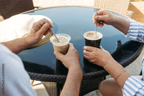 An elderly couple, a man and a woman, are drinking frappuccino and cappuccino. photo