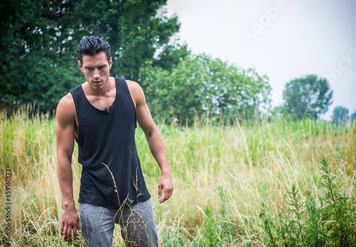 A man standing in a field of tall grass, during an adventurous trip, maybe he's lost